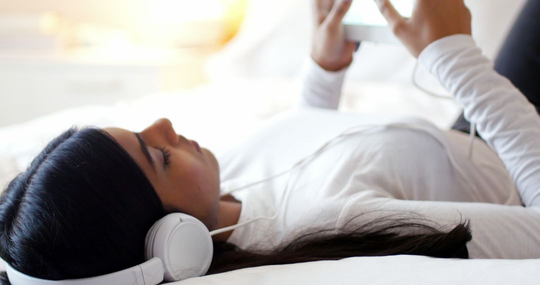 Woman Listening to Music with Headphones and Tablet Device on Bed - Free Images, Stock Photos and Pictures on Pikwizard.com