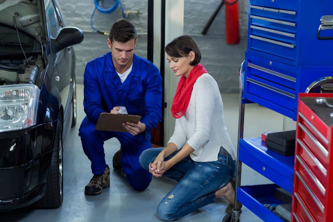 Mechanic showing checklist to customer in repair garage - Free Images, Stock Photos and Pictures on Pikwizard.com