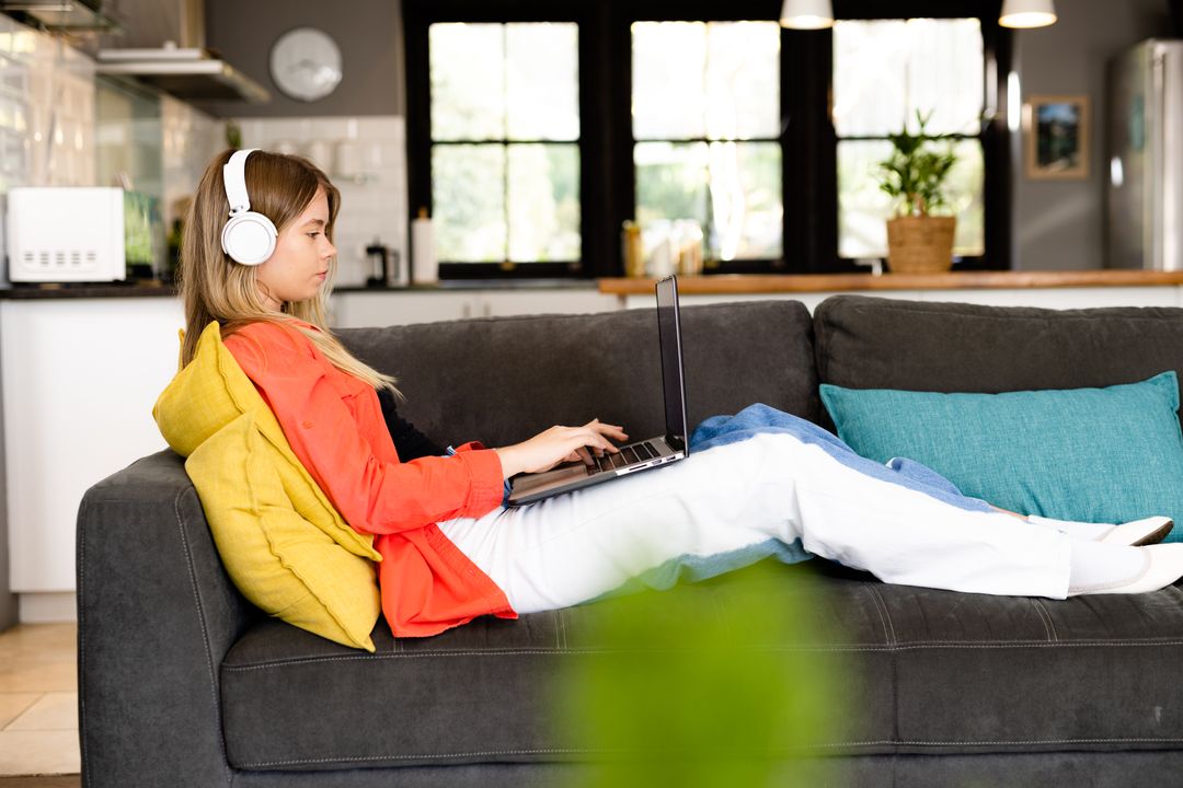 Teenage Girl Relaxing on Couch with Laptop and Headphones - Free Images, Stock Photos and Pictures on Pikwizard.com