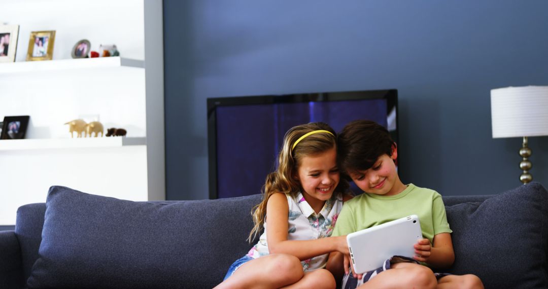 Happy Children Sitting on Couch Using Tablet in Living Room - Free Images, Stock Photos and Pictures on Pikwizard.com