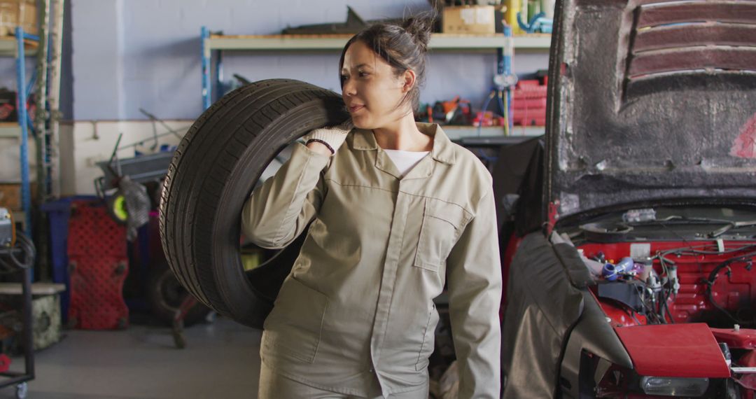 Female Mechanic Working in Auto Repair Shop Carrying Tire - Free Images, Stock Photos and Pictures on Pikwizard.com