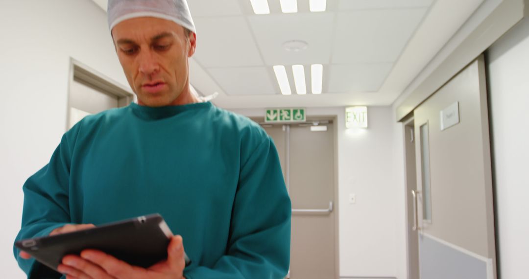 Male Surgeon Using Digital Tablet in Hospital Corridor - Free Images, Stock Photos and Pictures on Pikwizard.com