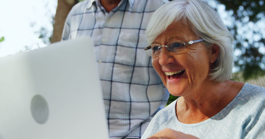 Senior woman smiling at laptop screen outdoors - Free Images, Stock Photos and Pictures on Pikwizard.com