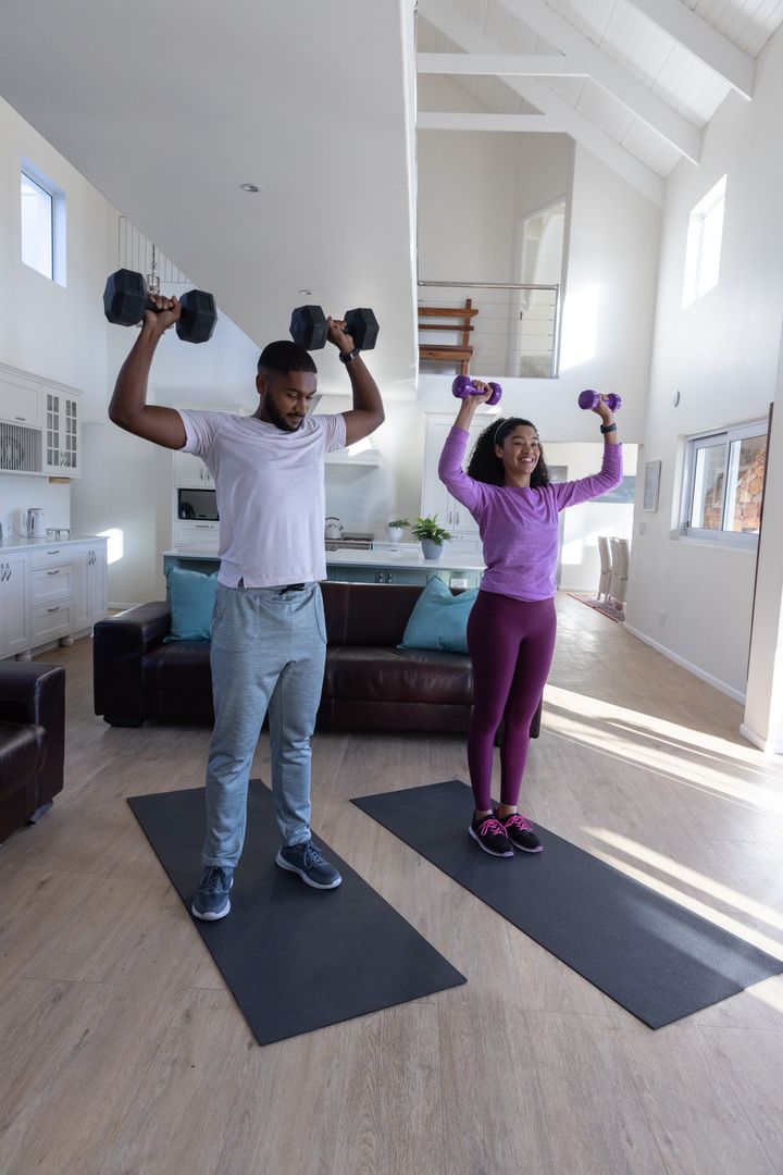 Diverse Couple Exercising with Dumbbells in Living Room