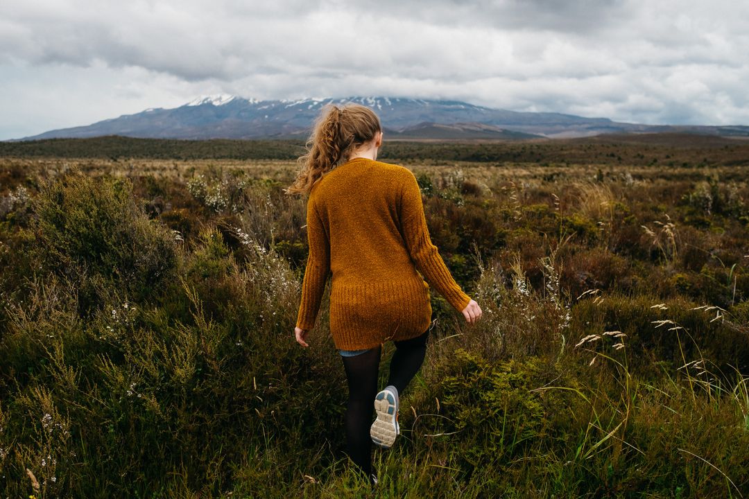 Woman Exploring Wild Field with Mountains in Background