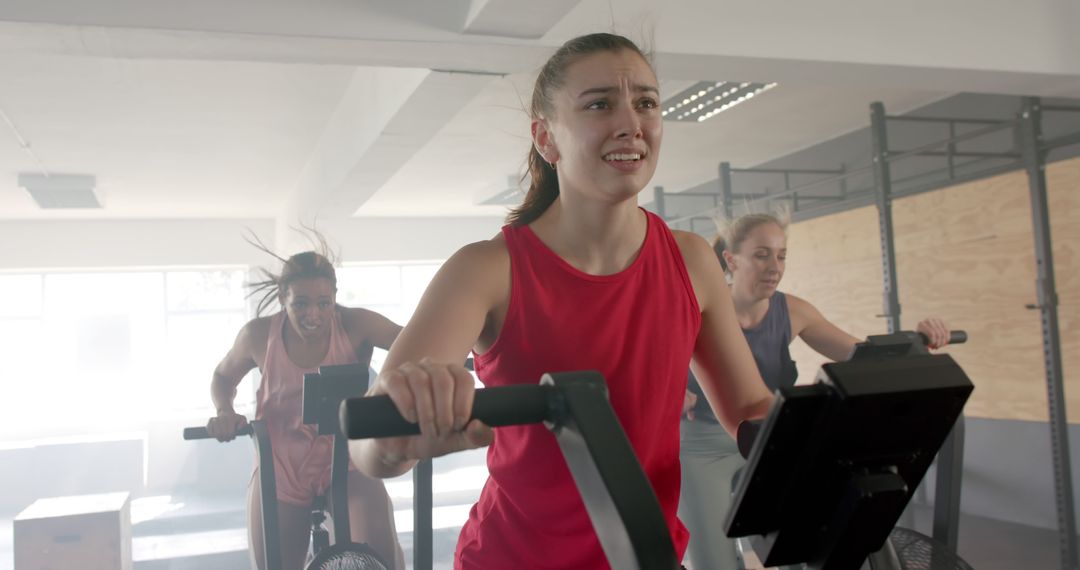 Young Women Exercising on Stationary Bikes in Gym - Free Images, Stock Photos and Pictures on Pikwizard.com