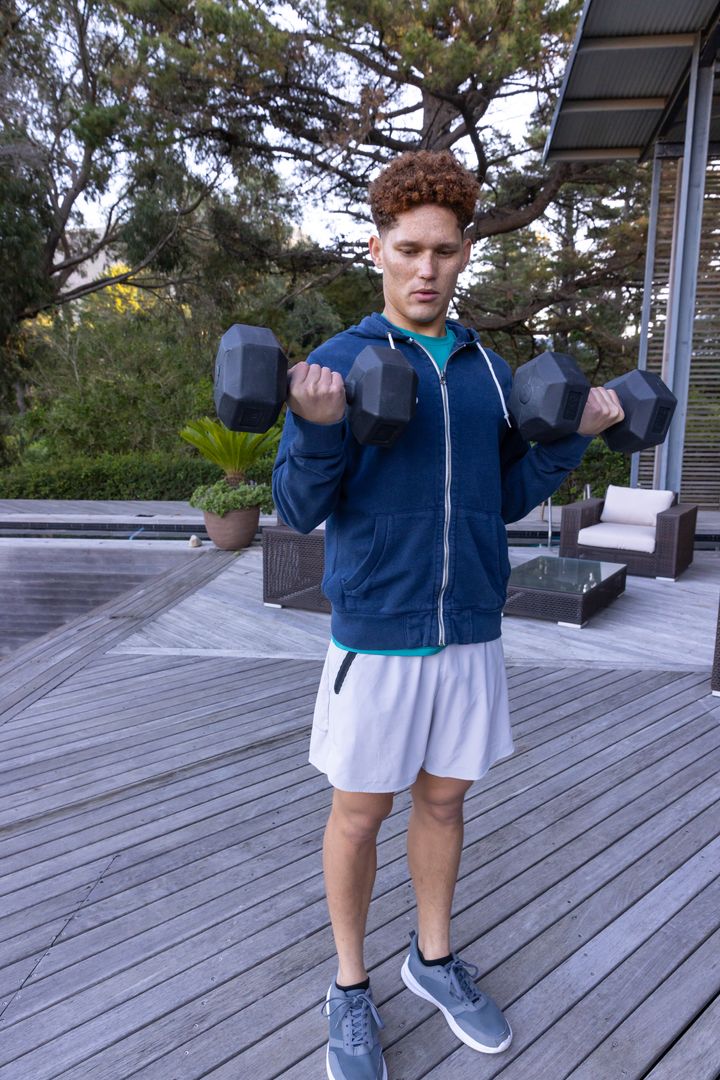 Man Exercising with Dumbbells on Outdoor Wooden Deck