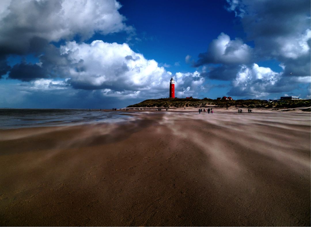 Vibrant Beach Scene with Iconic Red Lighthouse and Dynamic Clouds - Free Images, Stock Photos and Pictures on Pikwizard.com