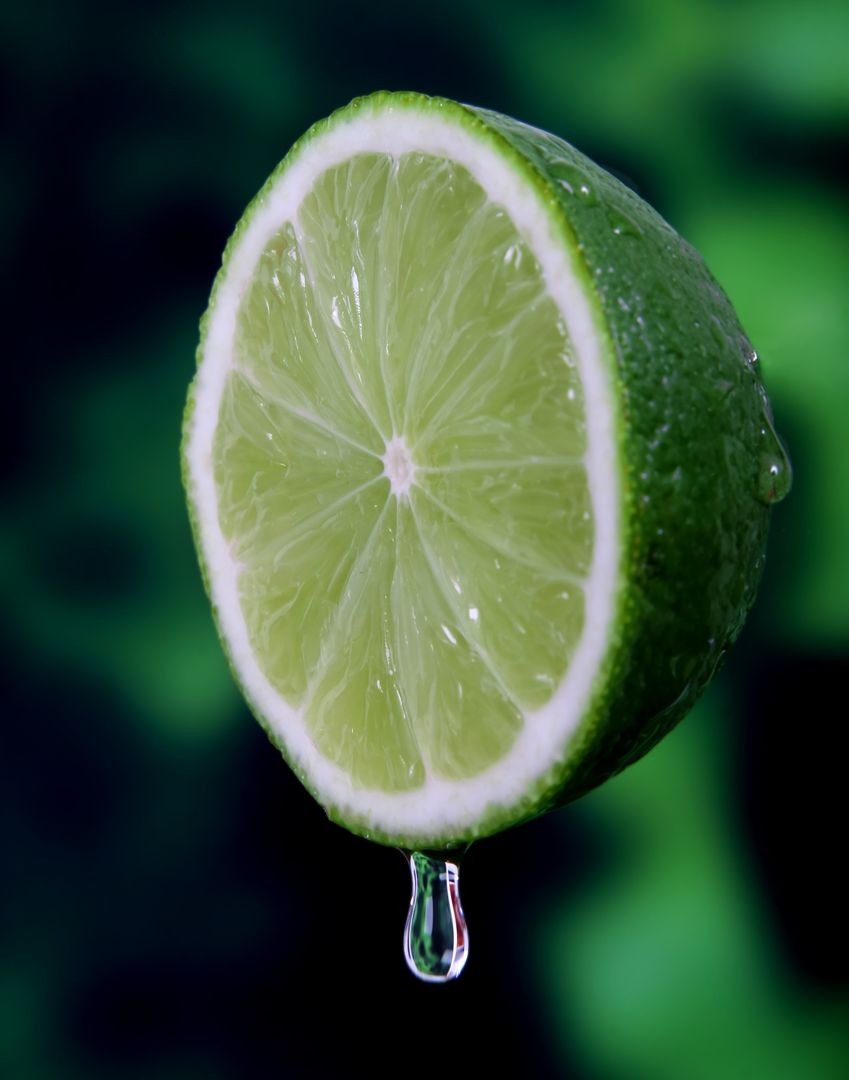 Fresh Lime Sliced with Dripping Juice against Green Background - Free Images, Stock Photos and Pictures on Pikwizard.com