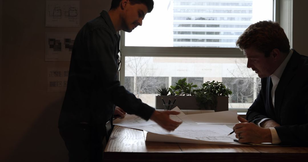 Architects Collaborating on Blueprint at Office Desk