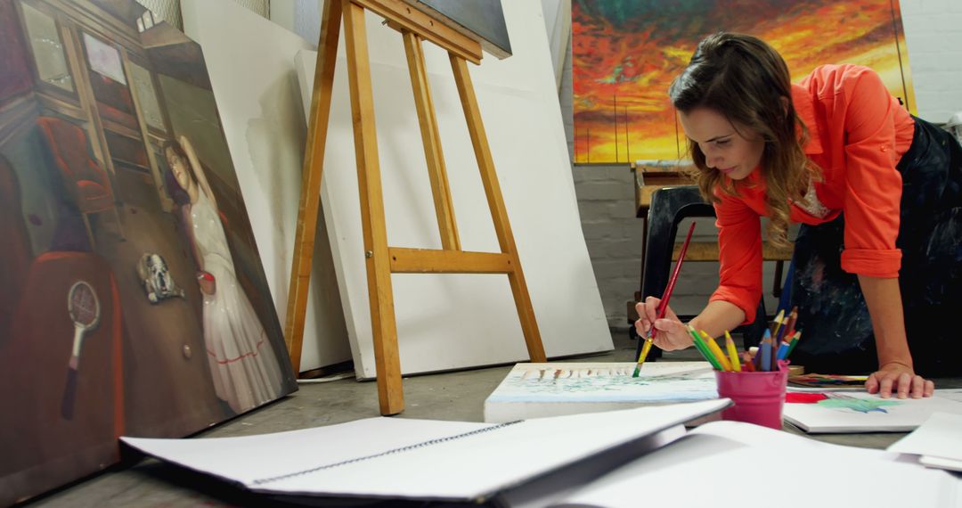 Female Artist Painting in Studio Surrounded by Canvas - Free Images, Stock Photos and Pictures on Pikwizard.com