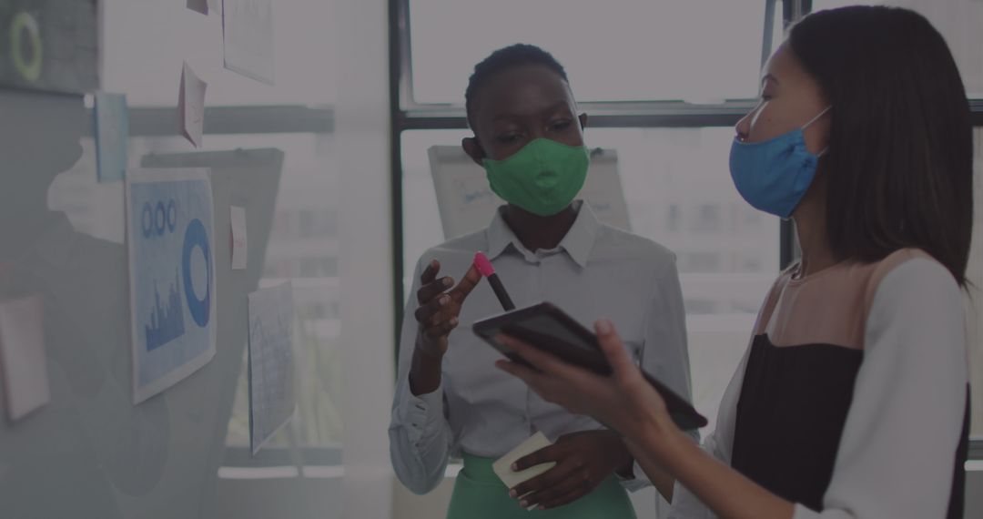 Businesswomen Collaborating on Financial Dashboard While Masked