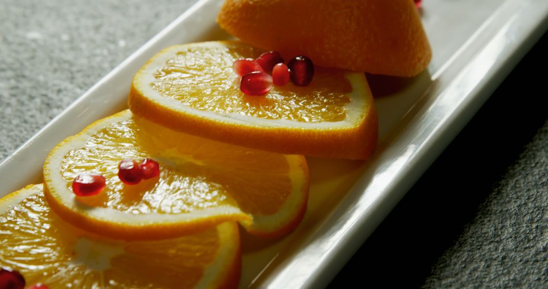 Top view of fresh orange slices and pomegranate seeds on a white plate - Free Images, Stock Photos and Pictures on Pikwizard.com