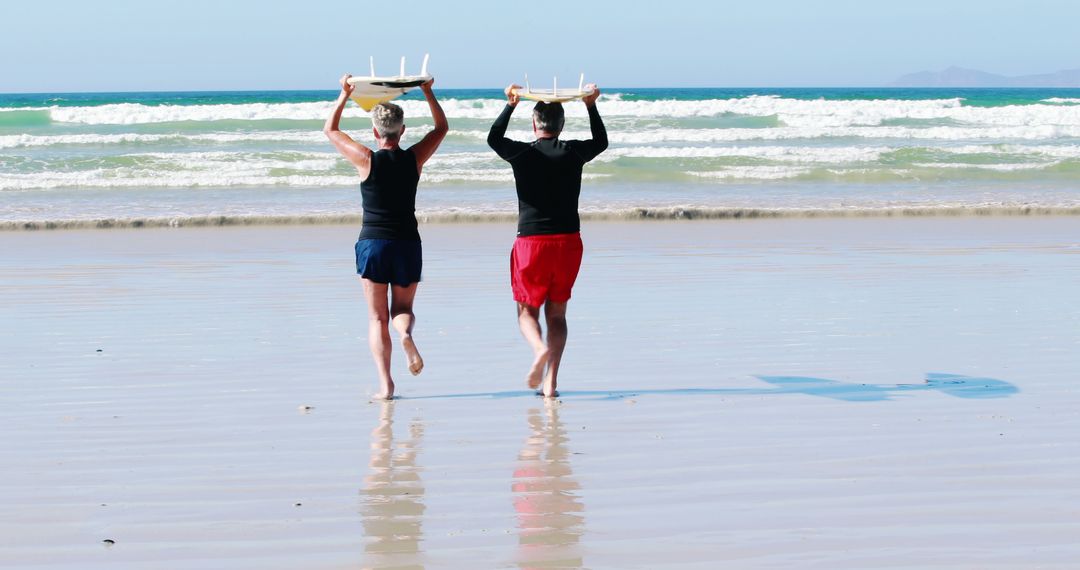 Two Surfers Carrying Surfboards on Sunny Beach - Free Images, Stock Photos and Pictures on Pikwizard.com