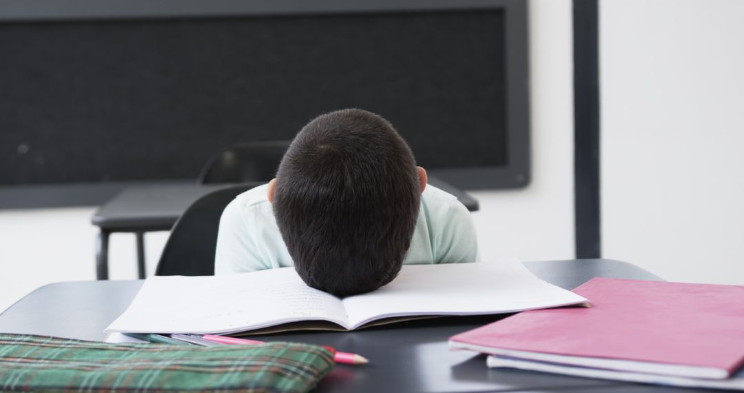 Young Student Falling Asleep on Desk During Classroom Study Session