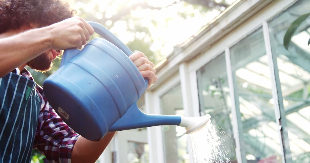 Man Watering Plants with Blue Watering Can in Garden - Free Images, Stock Photos and Pictures on Pikwizard.com