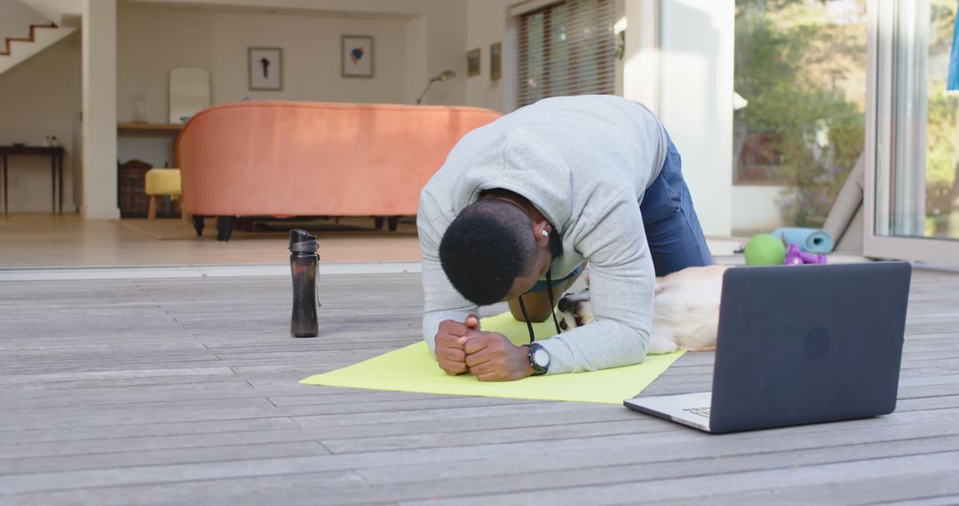 Man Exercising on Terrace with Laptop and Dog