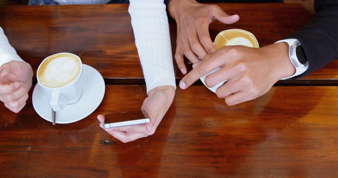 Two People Discussing over Coffee with Smartphone on Wooden Table - Free Images, Stock Photos and Pictures on Pikwizard.com