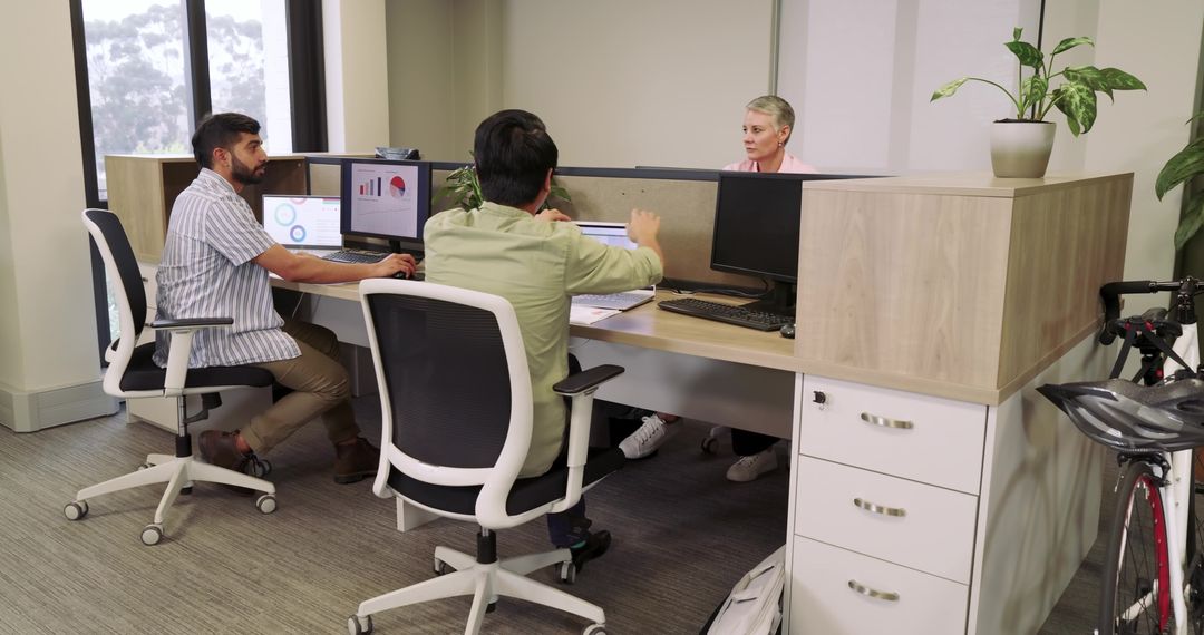 Modern Office Team Discussing Project Strategy at Shared Workstation