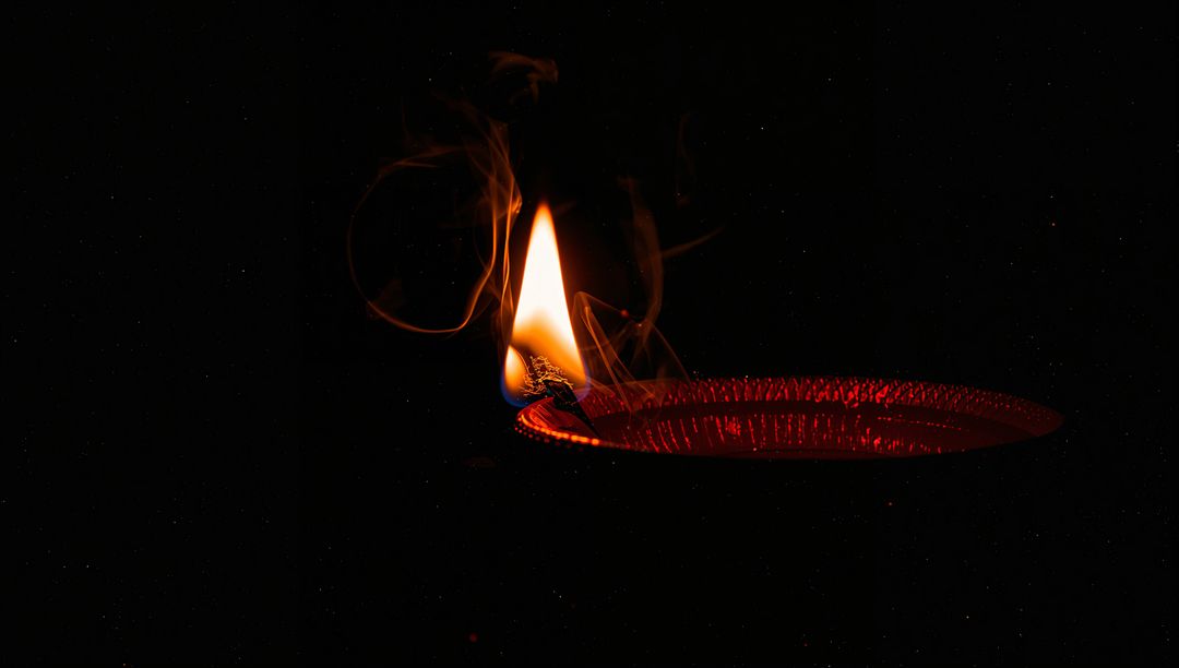 Burning Red Lamp with Flickering Flame and Smoke in Darkness