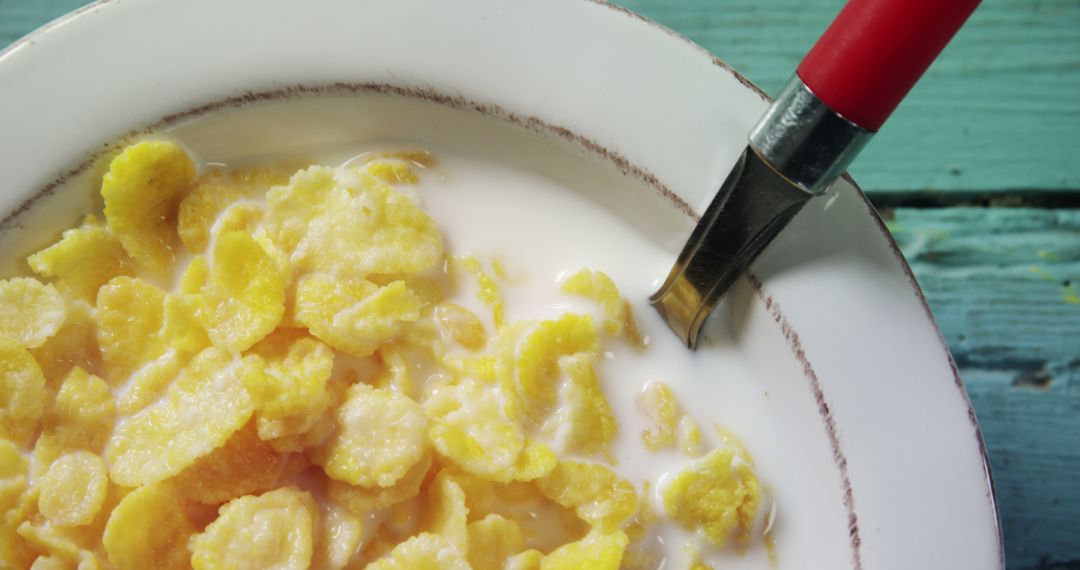 Close-Up of Cornflakes in Milk with Red-Handed Spoon on Wooden Table - Free Images, Stock Photos and Pictures on Pikwizard.com