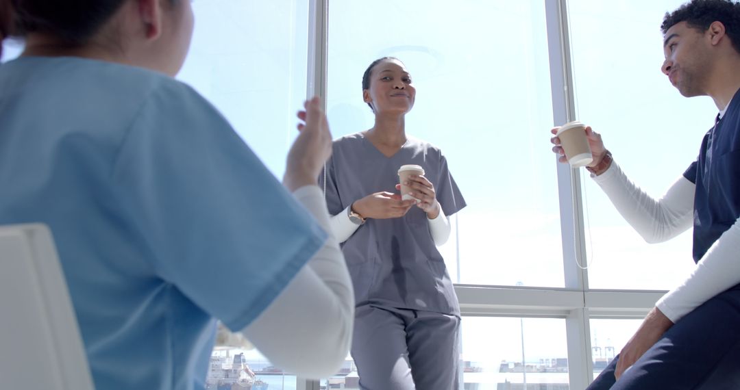 Medical Professionals Taking Coffee Break and Chatting by Window - Free Images, Stock Photos and Pictures on Pikwizard.com