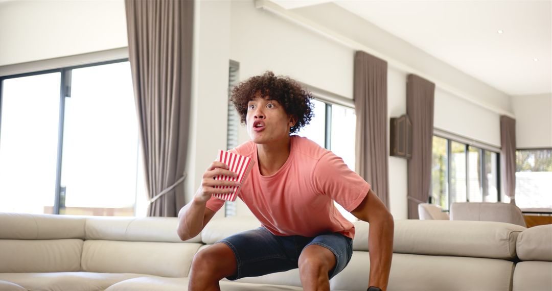 Excited Young Man Watching TV with Popcorn at Home
