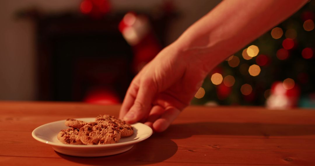 Hand Placing Cookies on Christmas Plate by Festive Decorations - Free Images, Stock Photos and Pictures on Pikwizard.com