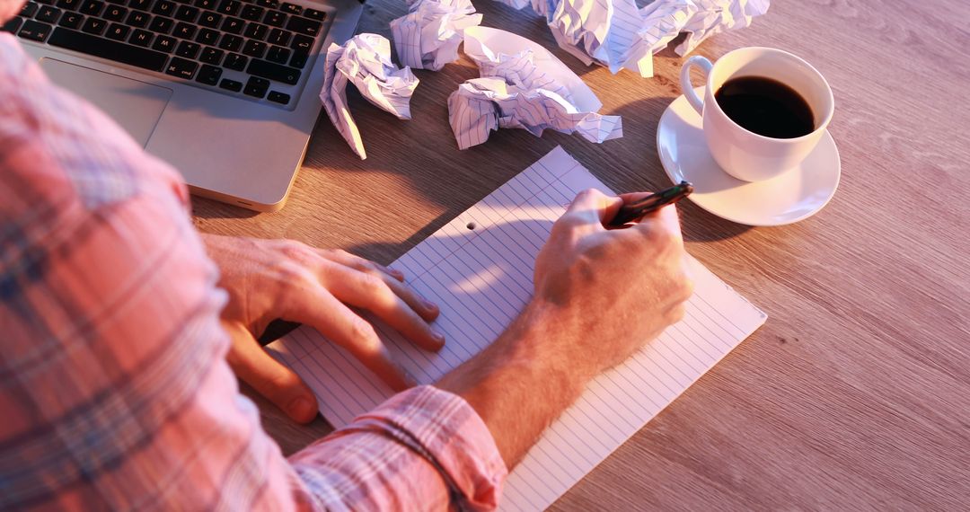 Man Writing on Notebook Next to Laptop and Coffee - Free Images, Stock Photos and Pictures on Pikwizard.com