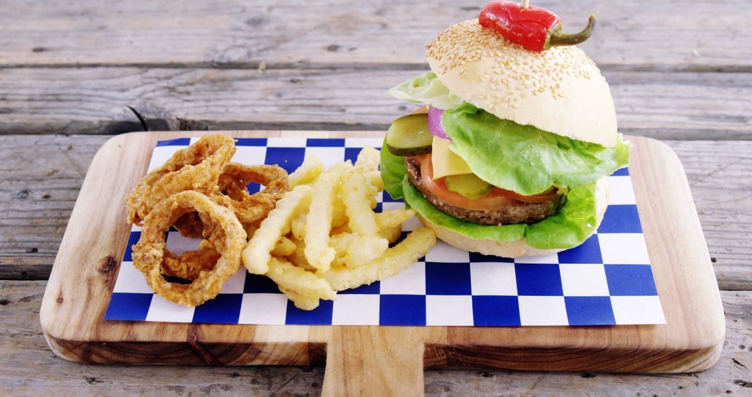 Fresh Cheeseburger with Onion Rings and Fries on Wooden Board