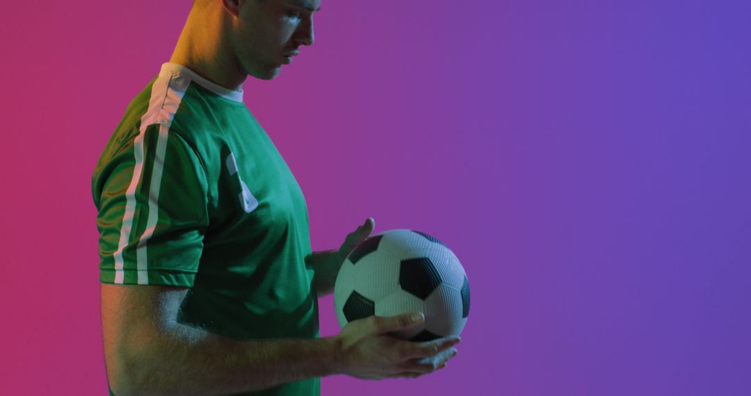 Focused Soccer Player Holding Football on Gradient Background