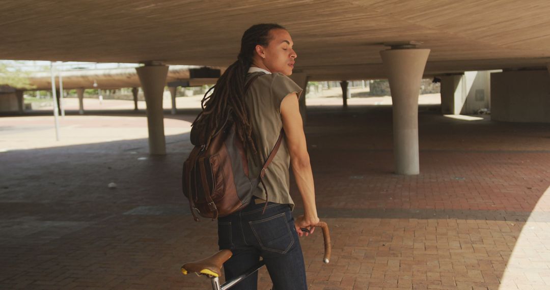 Young man with dreadlocks biking in urban environment - Free Images, Stock Photos and Pictures on Pikwizard.com