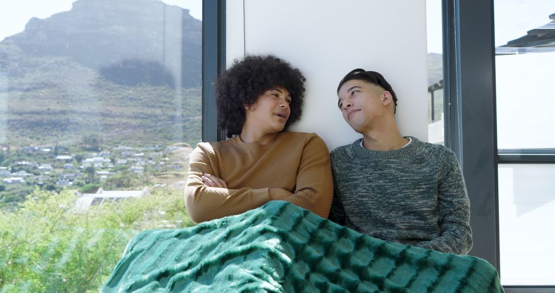 Friends Relaxing Under Blanket on Window Seat with Scenic View
