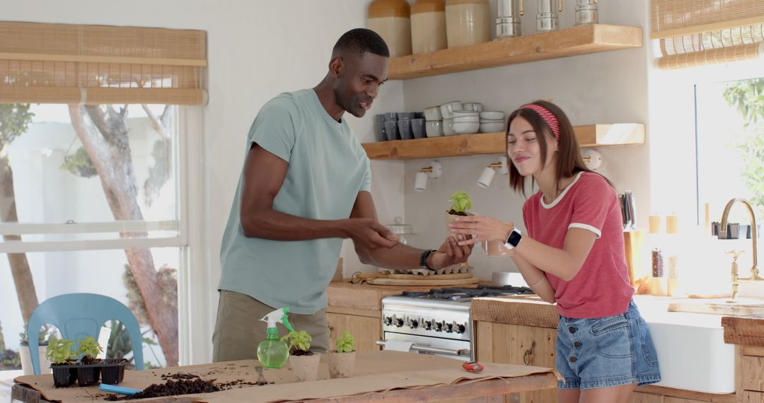 Diverse couple repotting seedlings in home kitchen for eco-friendly gardening