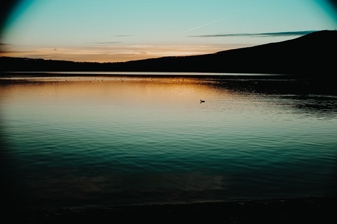 Tranquil Sunset Over Calm Lake with Silhouette of Distant Hills - Free Images, Stock Photos and Pictures on Pikwizard.com