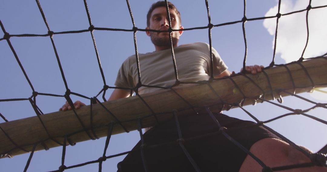 Man Climbing a Rope Net Against Blue Sky - Free Images, Stock Photos and Pictures on Pikwizard.com