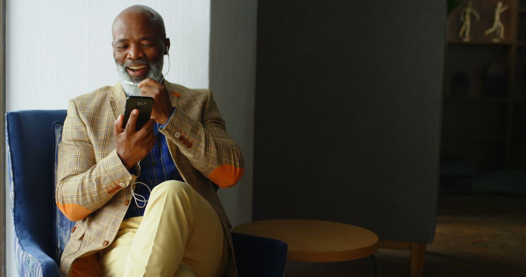 Elderly Man Enjoying Music on Smartphone in Modern Living Room - Free Images, Stock Photos and Pictures on Pikwizard.com