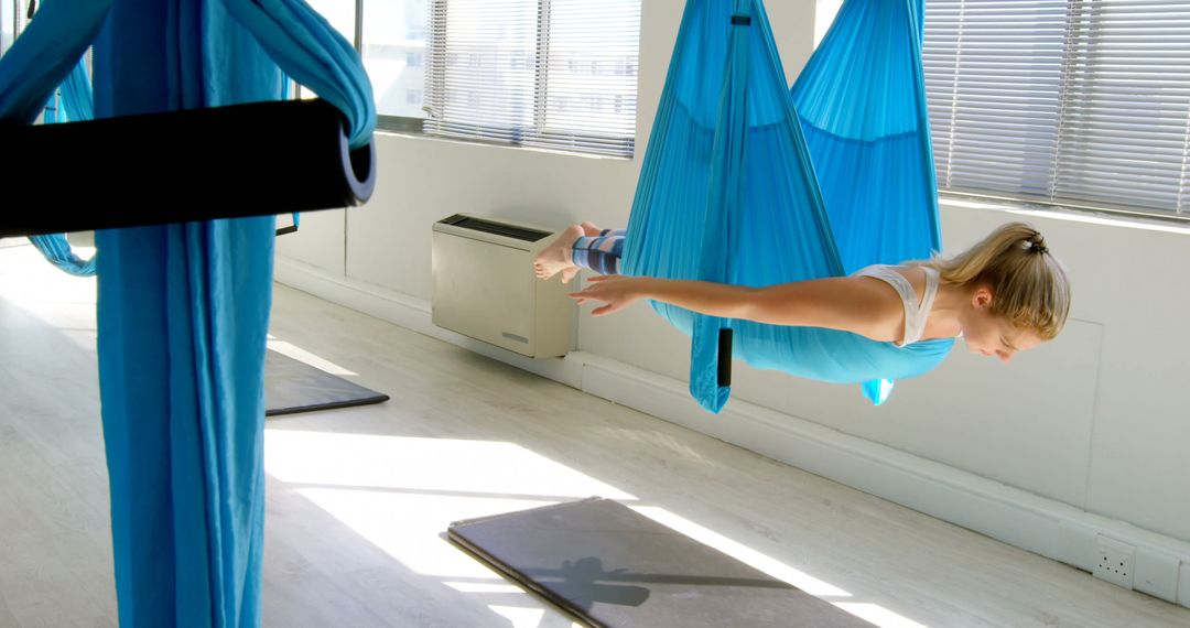 Caucasian Woman Practicing Aerial Yoga in Modern Gym - Free Images, Stock Photos and Pictures on Pikwizard.com