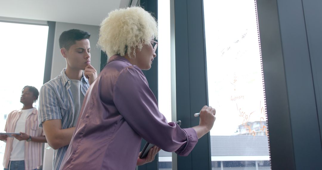 Diverse Team Collaborating on Glass Board in Office