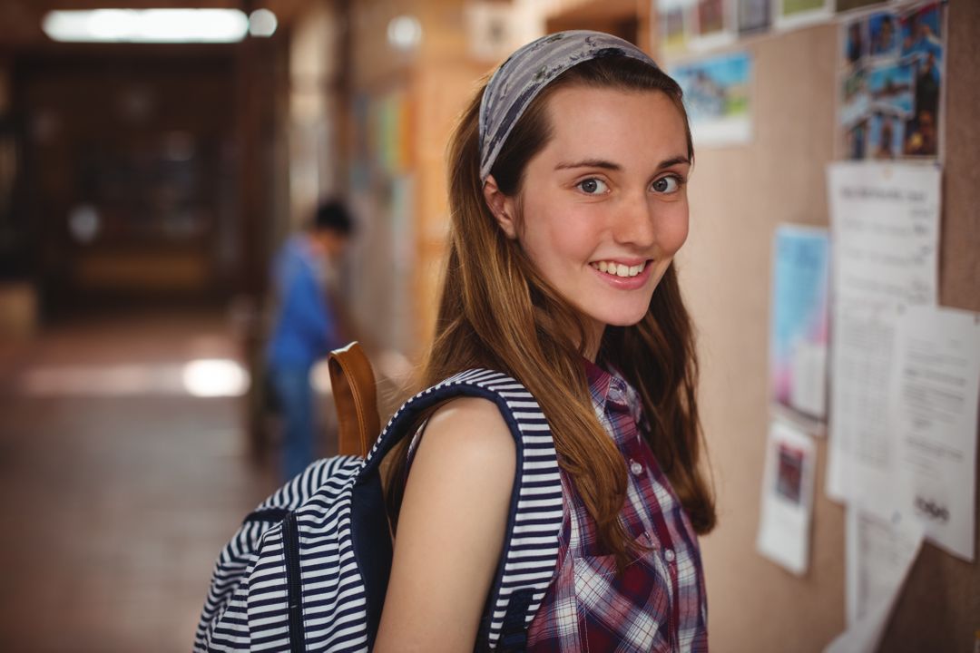 Smiling Schoolgirl Standing Near Notice Board in School Corridor - Free Images, Stock Photos and Pictures on Pikwizard.com