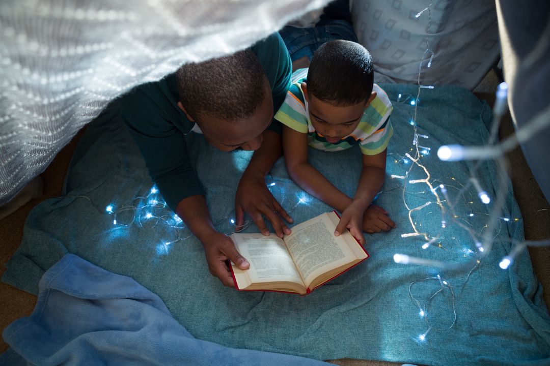 Father and Son Reading Book in Cozy Fort with Fairy Lights - Free Images, Stock Photos and Pictures on Pikwizard.com