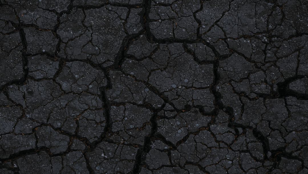 Dark Cracked Asphalt Texture with Deep Fissures and Loose Gravel