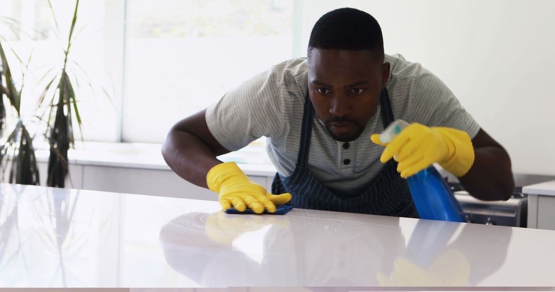 Focused African American Man Cleaning Kitchen Countertop - Free Images, Stock Photos and Pictures on Pikwizard.com