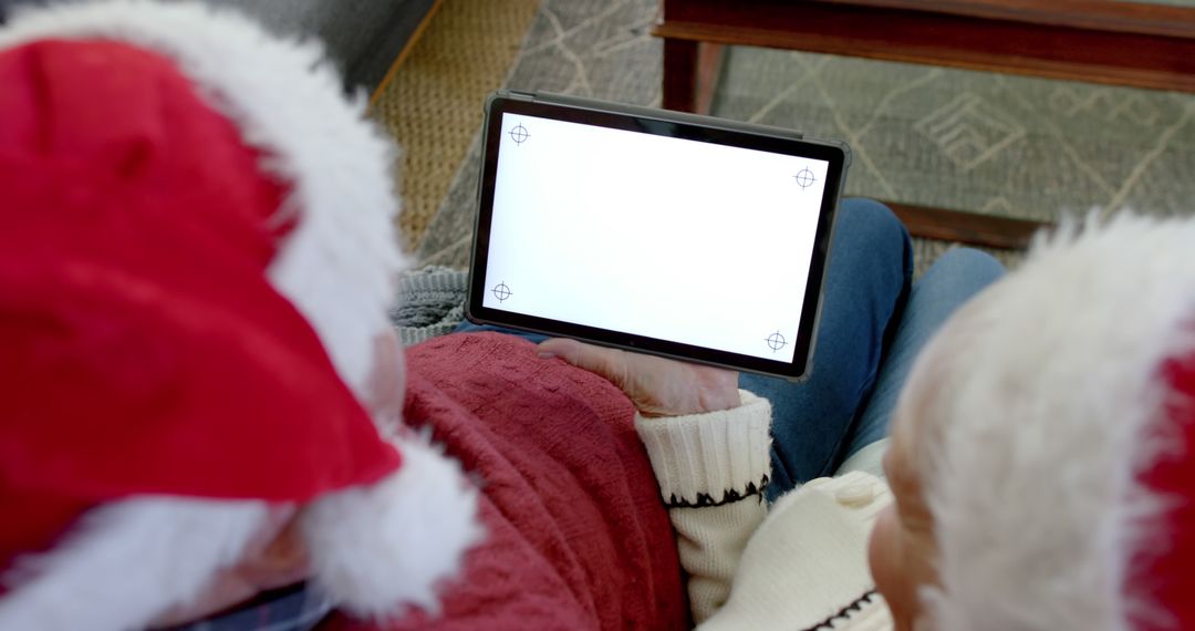 Couple Watching Tablet in Christmas Hats with Blank Screen - Free Images, Stock Photos and Pictures on Pikwizard.com