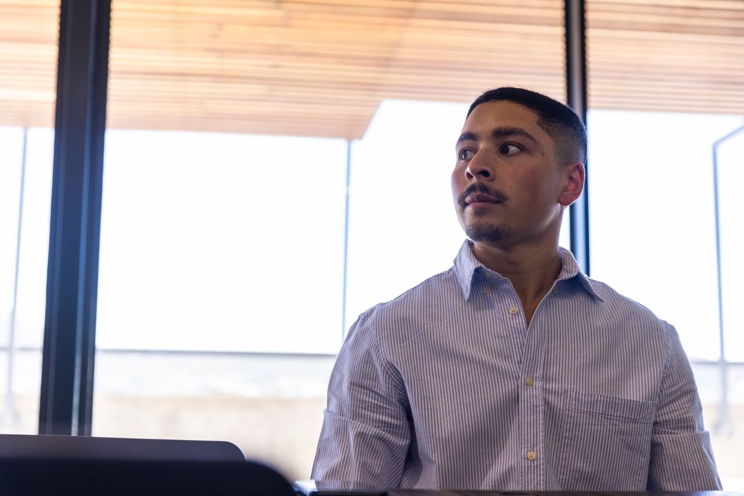 Focused Employee Working at Modern Office Desk by Large Windows