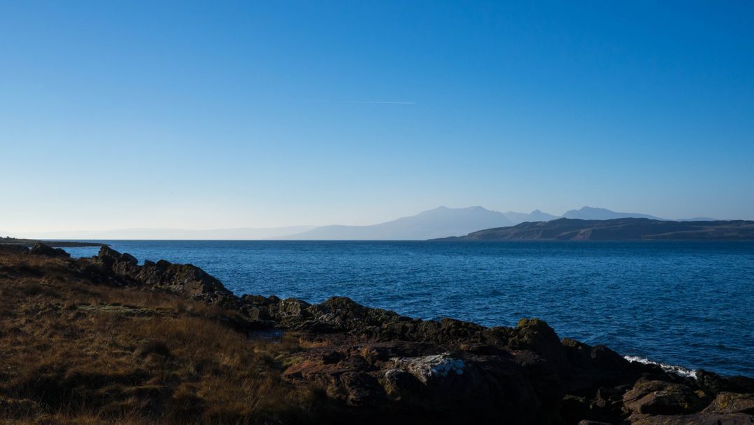 Tranquil Coastal View with Distant Mountains and Clear Blue Sky - Free Images, Stock Photos and Pictures on Pikwizard.com