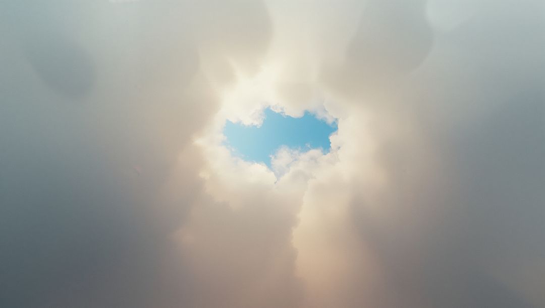 Sunlight Filtering Through Circular Cloud Opening to Blue Sky