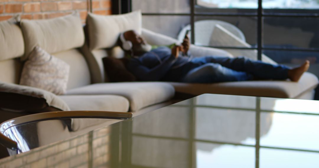 Person Relaxing on Sofa with Headphones and Smartphone - Free Images, Stock Photos and Pictures on Pikwizard.com