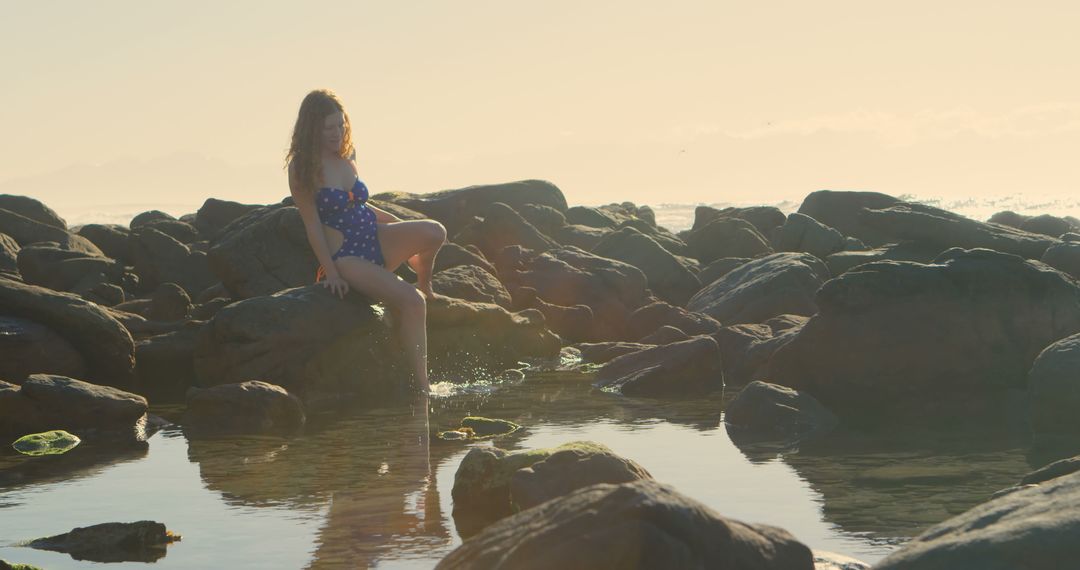 Woman Relaxing on Seaside Rocks at Sunset with Tranquil View