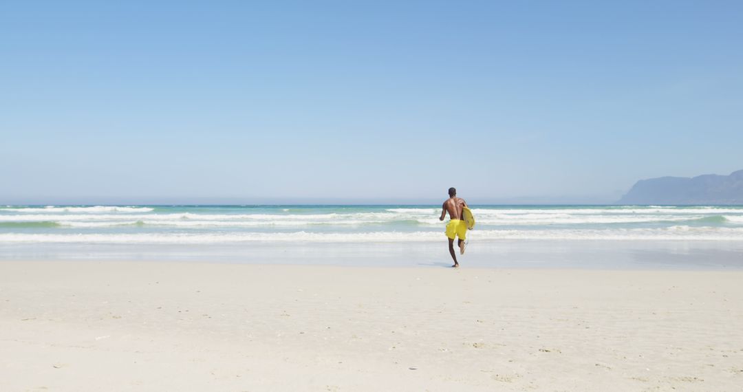 Man Running Towards Ocean on Sunny Beach - Free Images, Stock Photos and Pictures on Pikwizard.com